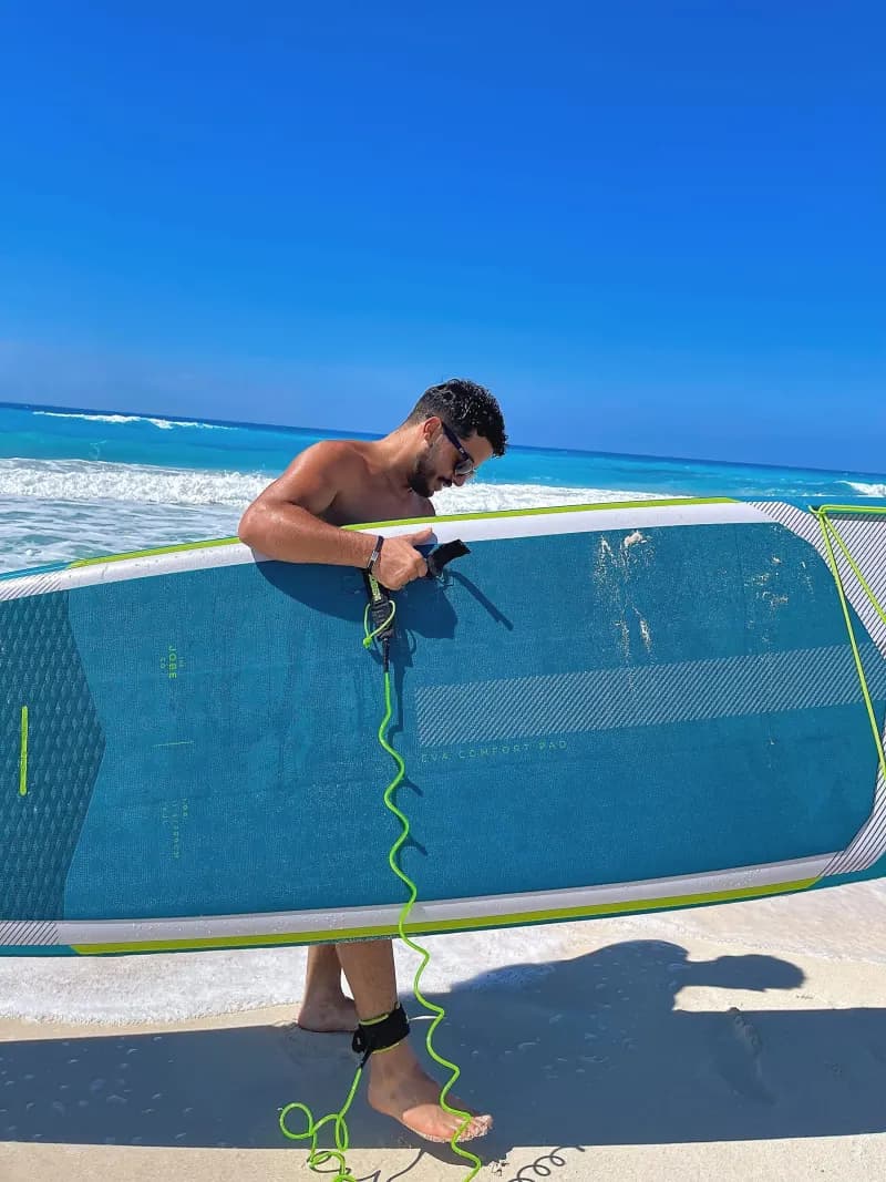 A guest carrying a paddle board on the Red Sea