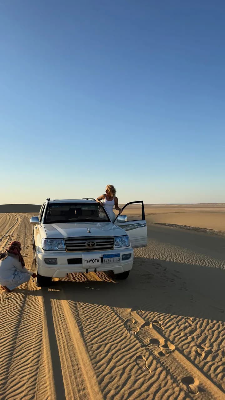 A 4x4 stopped on the sand before the dunes